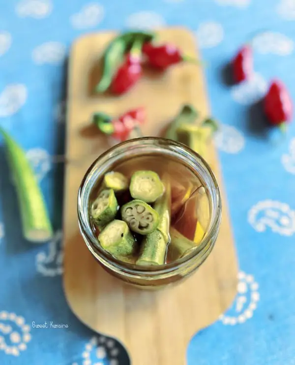 pickles de gombo sur planche en bois avec fond bleu et piments